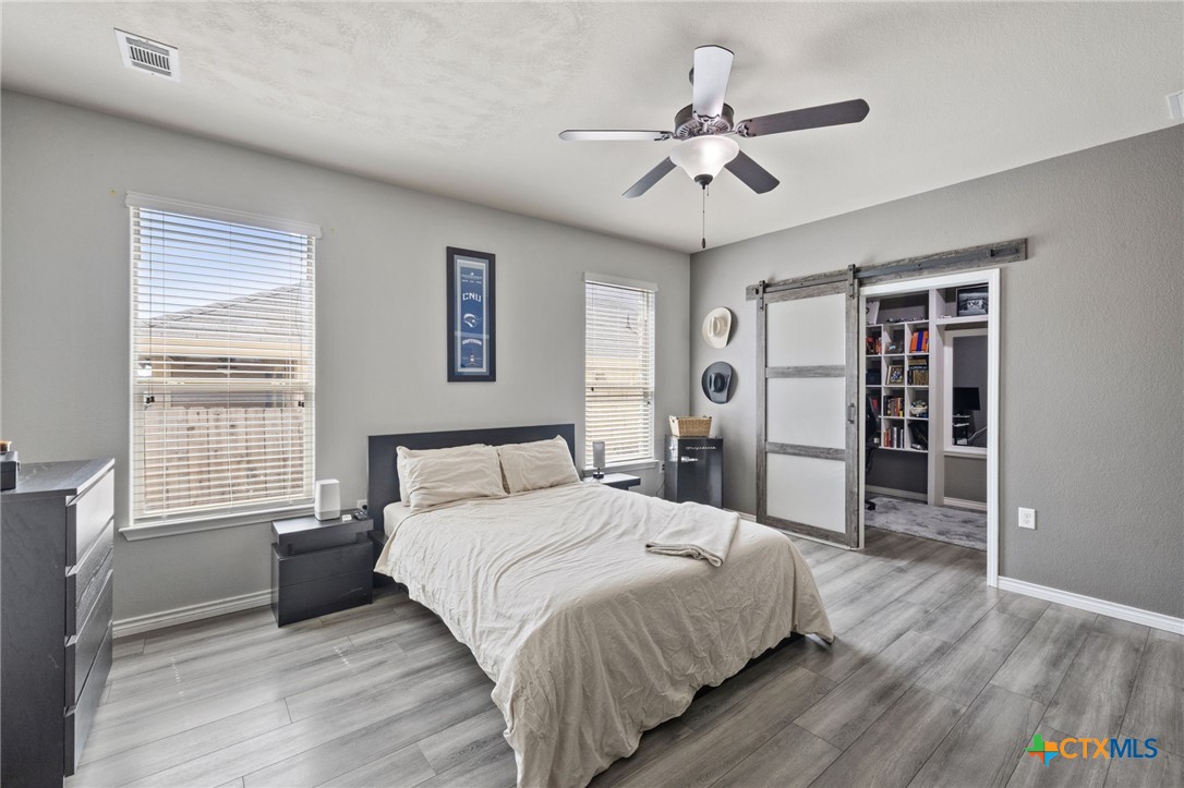 10113 Copper Ridge Cove Austin, TX 78747 - Photo 24 of 32 a bedroom with a large bed and a ceiling fan