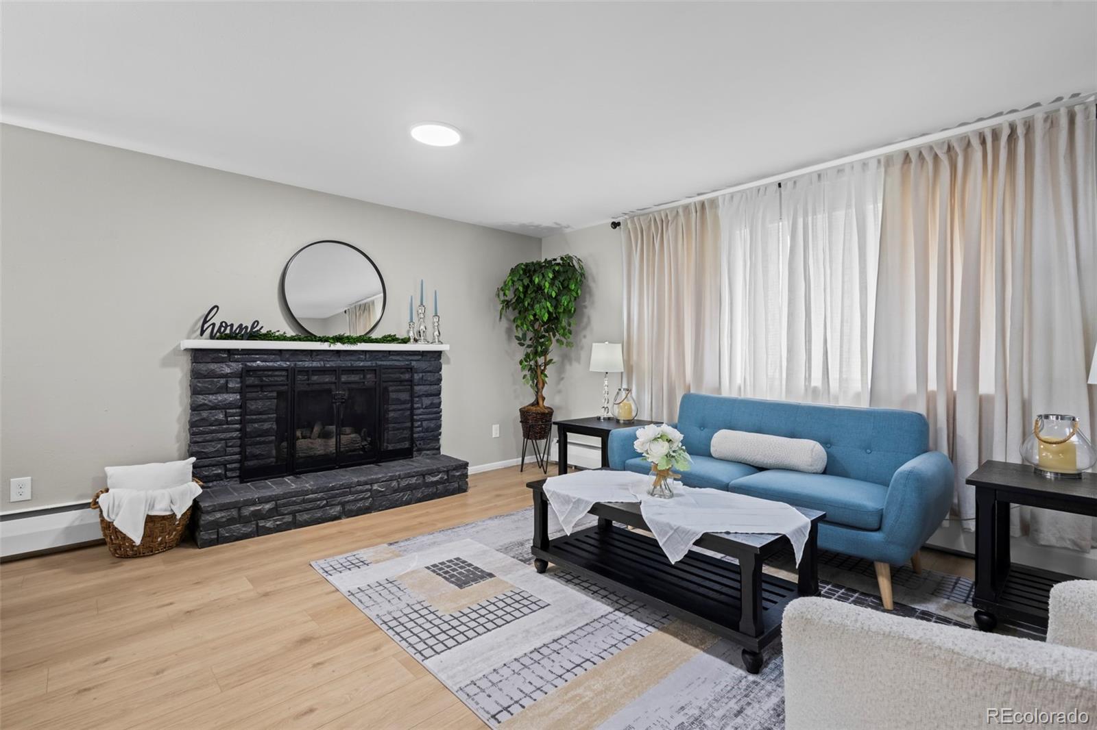 390 Scranton Street Aurora, CO 80011 - Photo 2 of 45 a living room with furniture a fireplace a rug and a window