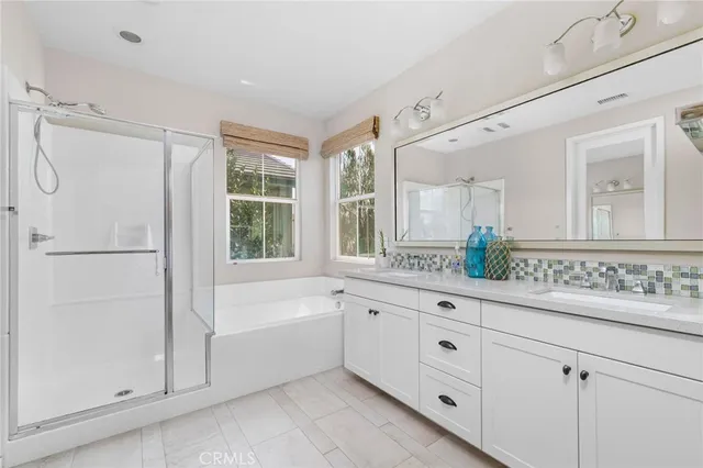 a bathroom with a double vanity sink and mirror with bathtub