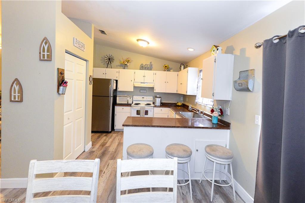 18347 Fuchsia Road Fort Myers, FL 33967 - Photo 25 of 35 a kitchen with stainless steel appliances granite countertop a refrigerator a stove and white cabinets with wooden floor