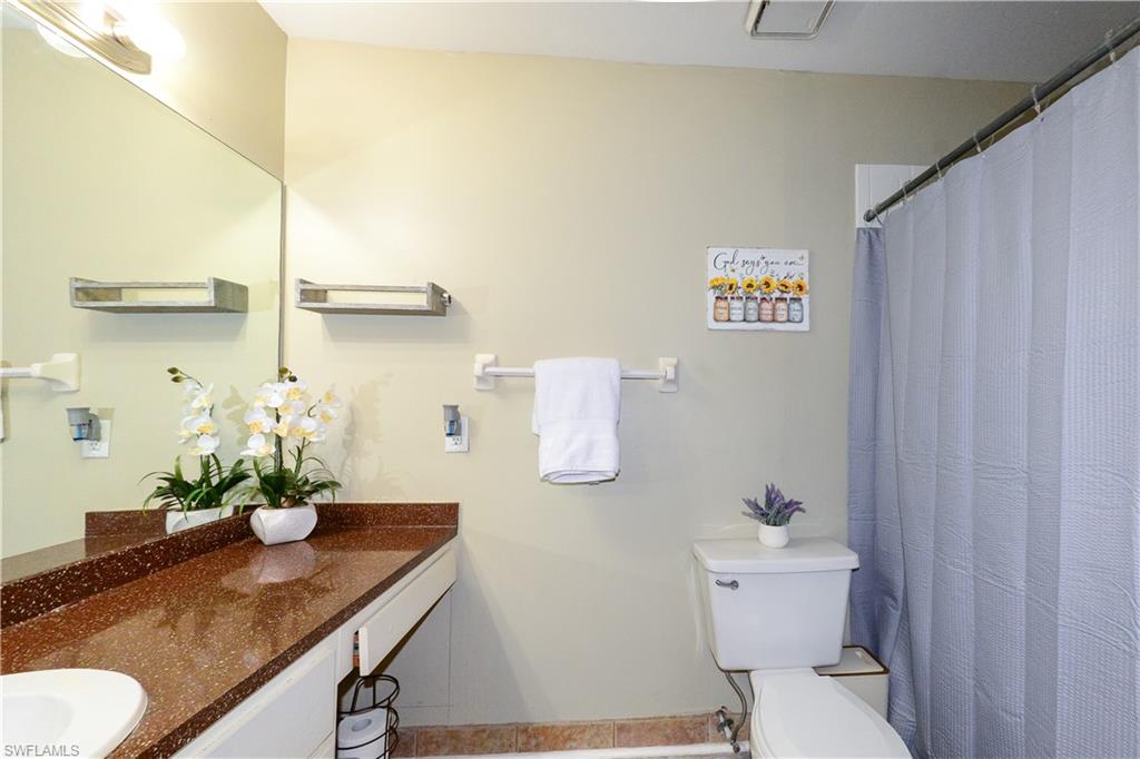 18347 Fuchsia Road Fort Myers, FL 33967 - Photo 8 of 35 a bathroom with a granite countertop sink a toilet and a mirror