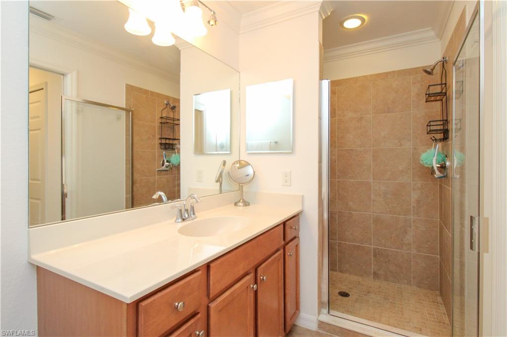 9554 Trevi Court, Unit 4737 Naples, FL 34113 - Photo 17 of 49 a bathroom with a sink vanity granite shower and a mirror