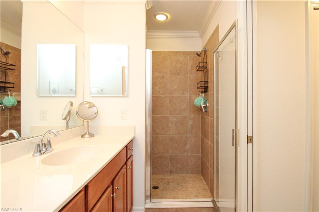 9554 Trevi Court, Unit 4737 Naples, FL 34113 - Photo 19 of 49 a bathroom with a granite countertop sink a mirror and shower