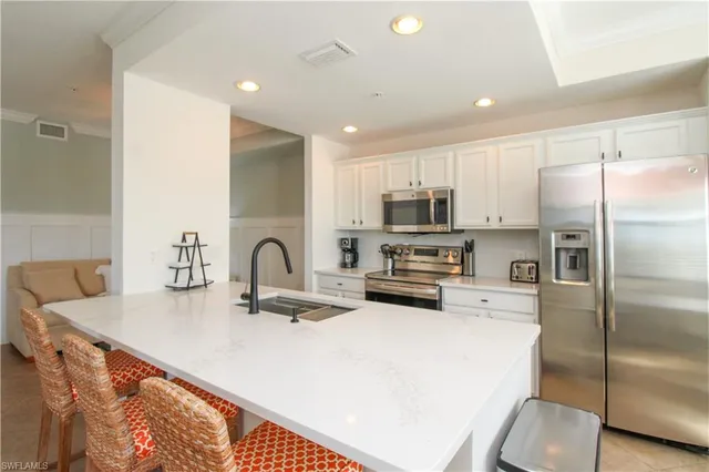a large kitchen with dining table chairs stainless steel appliances and cabinets