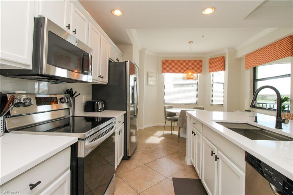 9554 Trevi Court, Unit 4737 Naples, FL 34113 - Photo 26 of 49 a kitchen with stainless steel appliances a sink a stove and a microwave