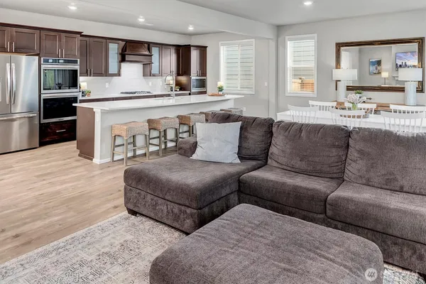 a living room with couches and kitchen view with wooden floor
