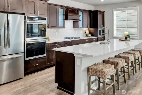 a kitchen with kitchen island a counter top space a sink stainless steel appliances and cabinets