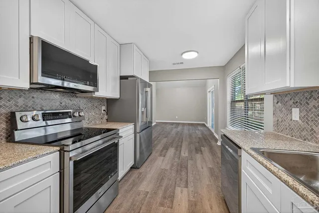 a kitchen with stainless steel appliances granite countertop a stove microwave and refrigerator