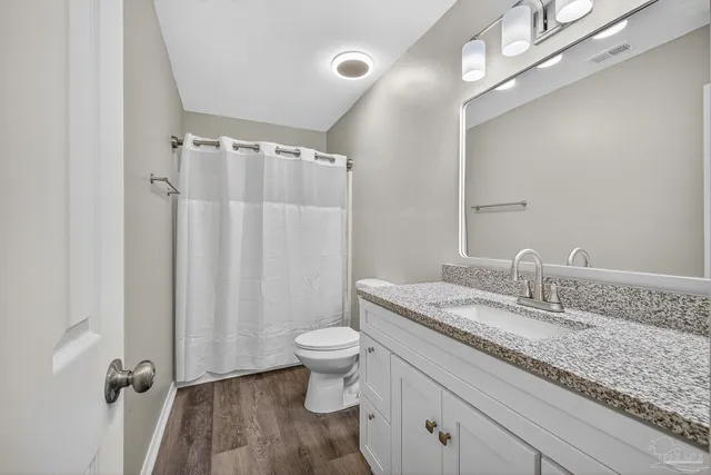a bathroom with a granite countertop sink toilet and shower