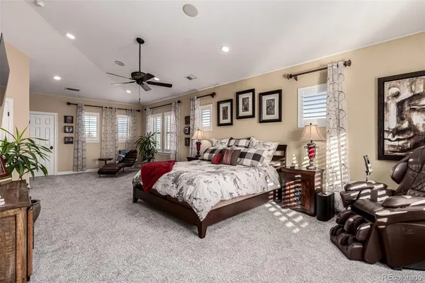 a spacious bedroom with a bed a couch and a potted plant on table