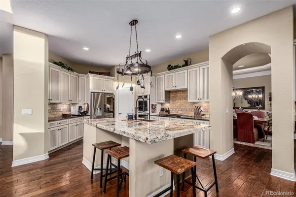 a kitchen with stainless steel appliances kitchen island granite countertop a table chairs and a refrigerator