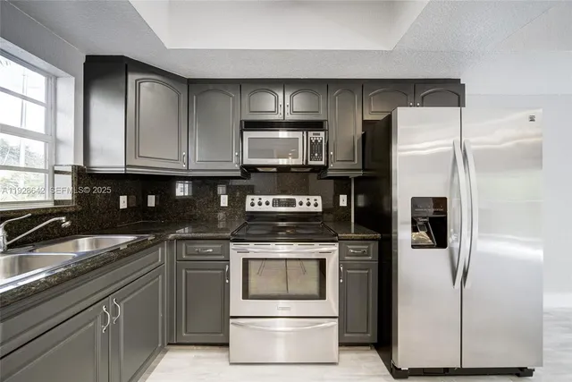 a kitchen with granite countertop a refrigerator stove and microwave