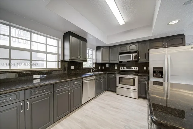a kitchen with granite countertop a refrigerator and a sink