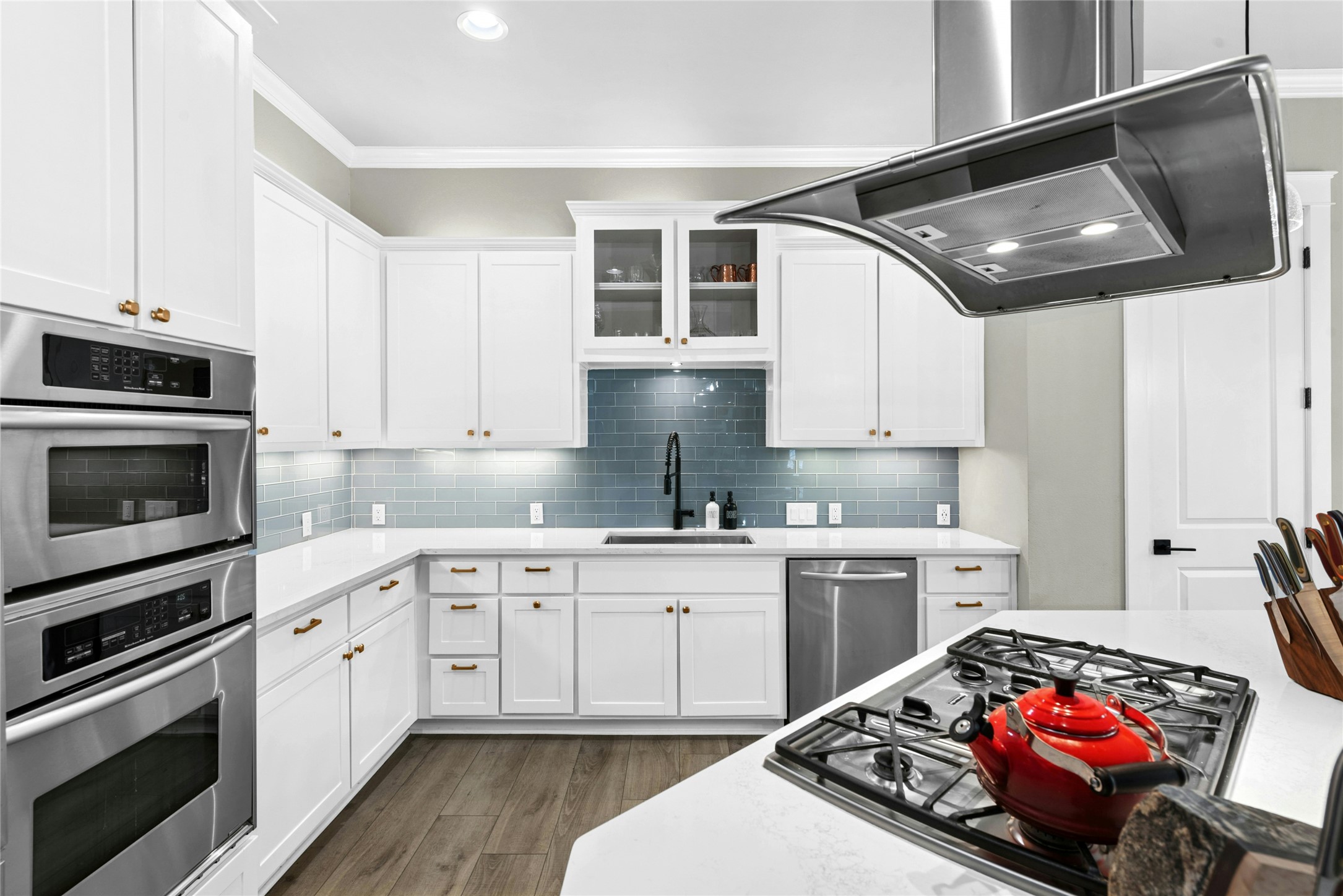 279 Rugged Earth Drive Austin, TX 78737 - Photo 16 of 40 a kitchen with stainless steel appliances a stove a sink dishwasher and white cabinets with wooden floor