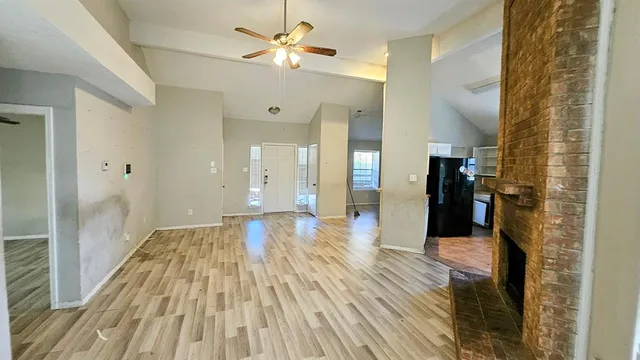 a view of a hallway with wooden floor and a bathroom