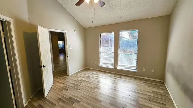 a view of an empty room with wooden floor closet and a window