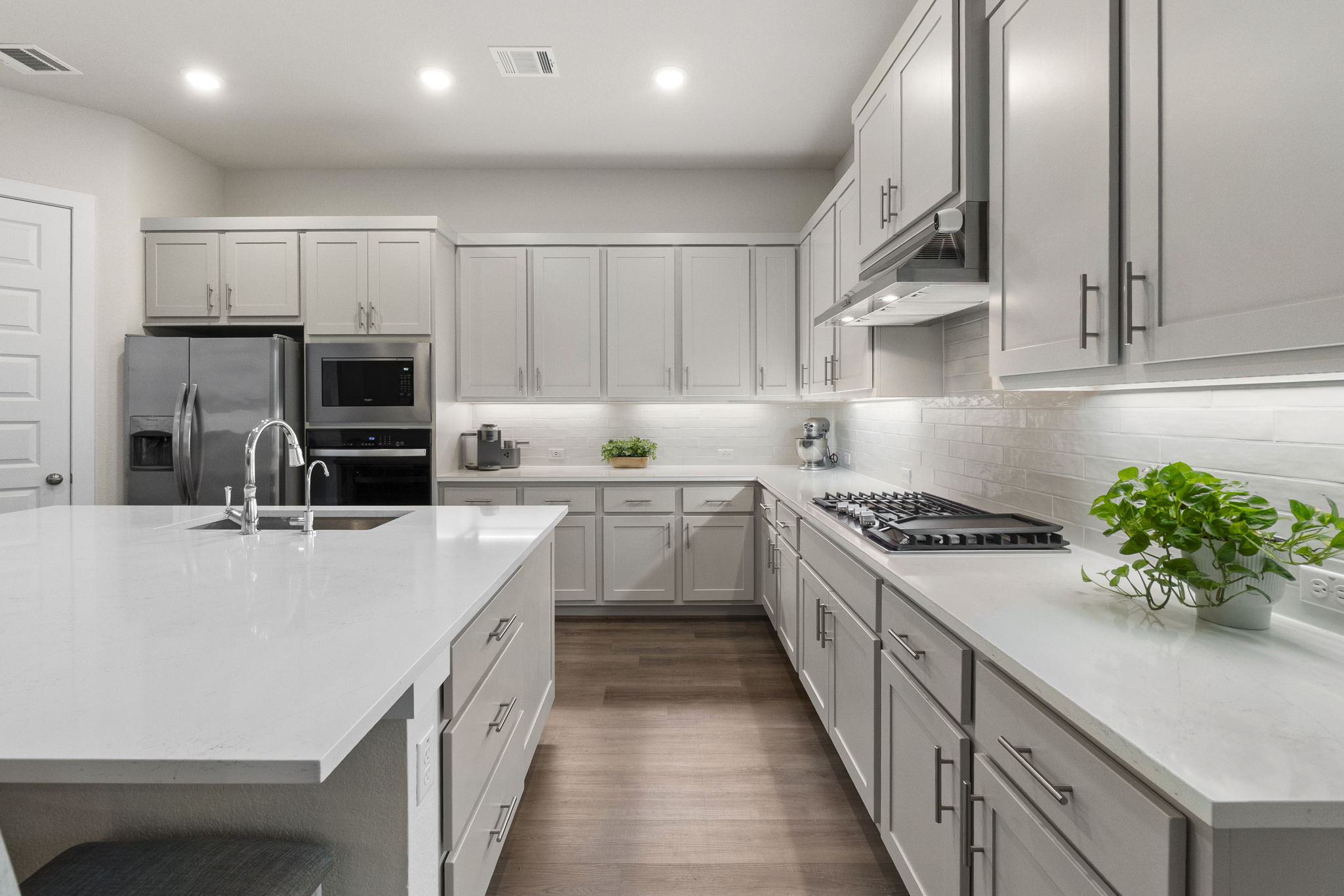 460 Constitution Way Kyle, TX 78640 - Photo 15 of 40 Modern kitchen featuring light gray cabinetry with brushed nickel hardware, white stone countertops, and a white subway tile backsplash