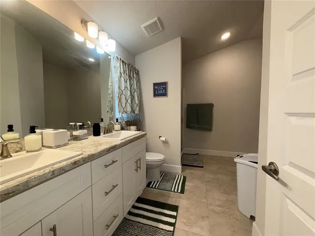 a spacious bathroom with a double vanity sink a mirror and a toilet