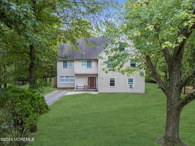a front view of a house with a garden and trees