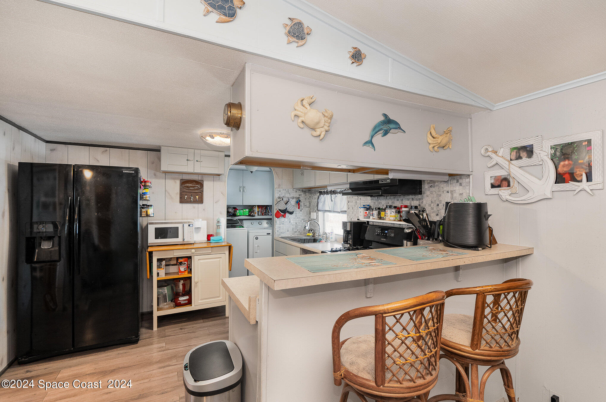 385 Ronald Street Cocoa, FL 32927 - Photo 7 of 24 a kitchen with stainless steel appliances kitchen island granite countertop a refrigerator a stove a sink and chairs with wooden floor