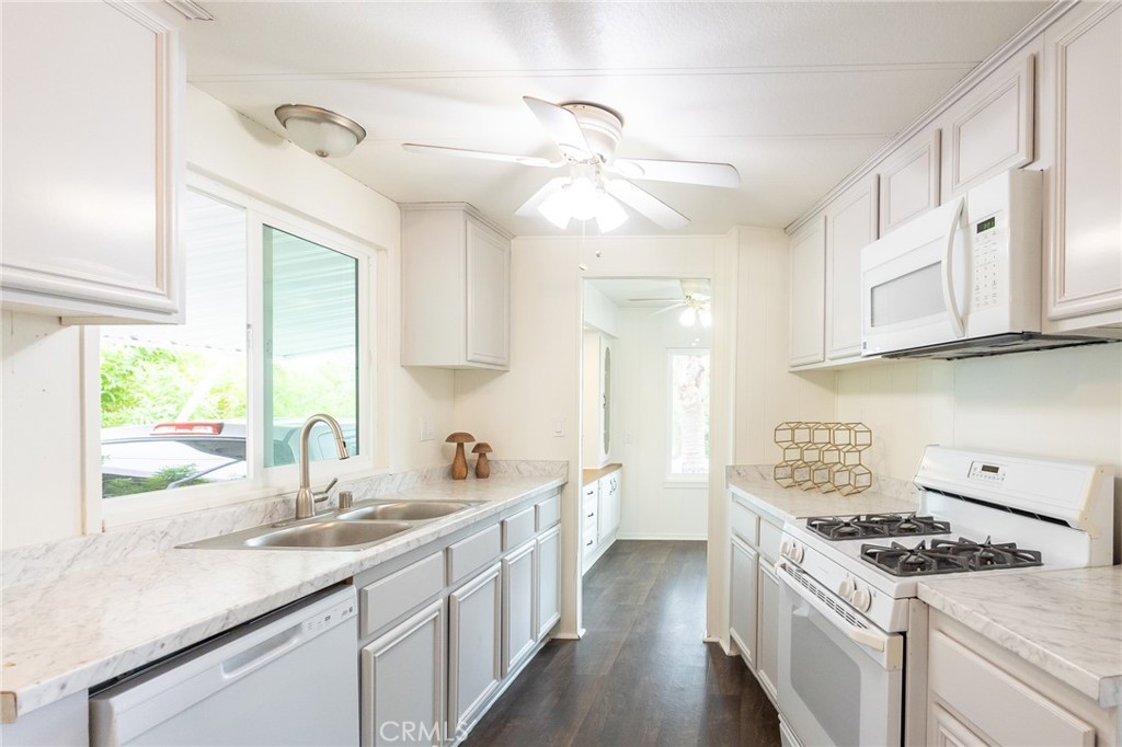 1134 Villa Calimesa Lane, Unit 106 Calimesa, CA 92320 - Photo 3 of 22 a kitchen with granite countertop a sink a stove cabinets and wooden floor