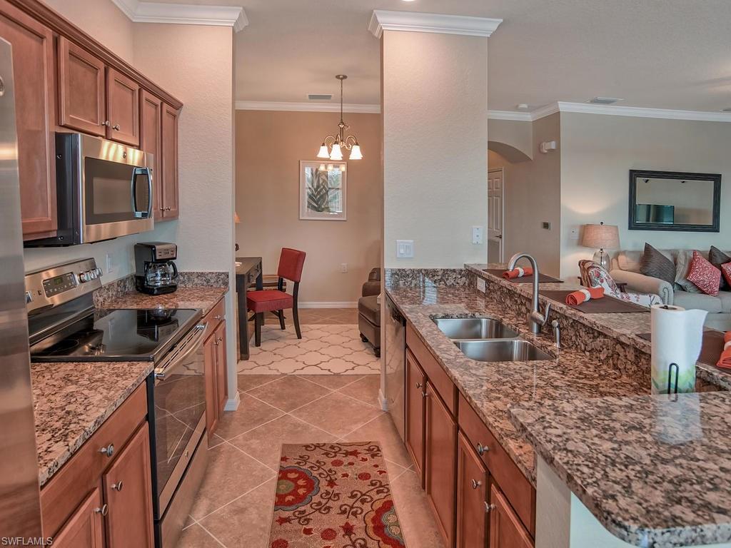 9560 Trevi Court, Unit 4842 Naples, FL 34113 - Photo 7 of 25 a kitchen with stainless steel appliances granite countertop a sink stove and refrigerator