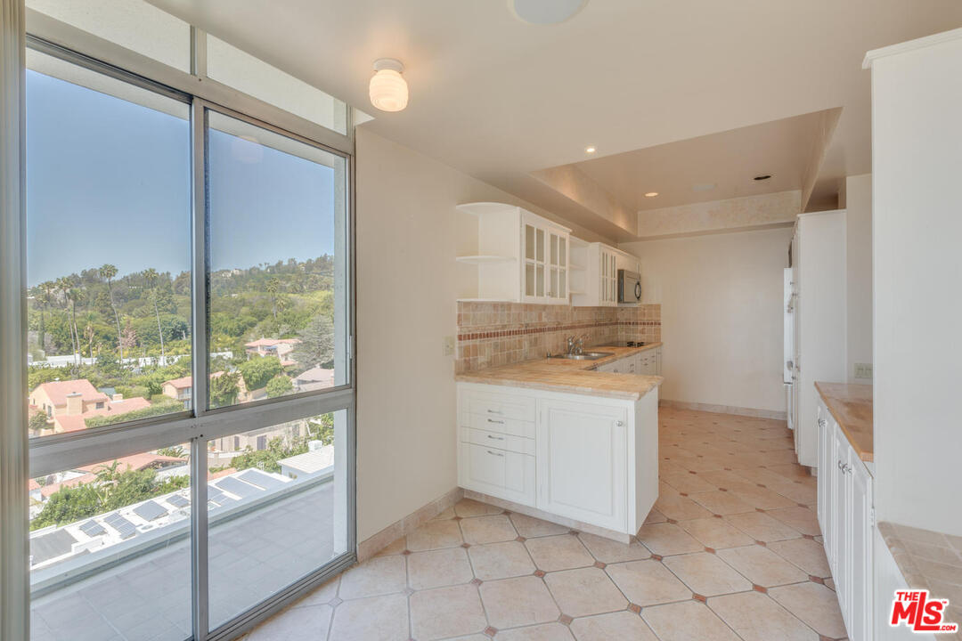 9255 Doheny Road, Unit 902 West Hollywood, CA 90069 - Photo 8 of 47 a kitchen with a stove a refrigerator and white cabinets