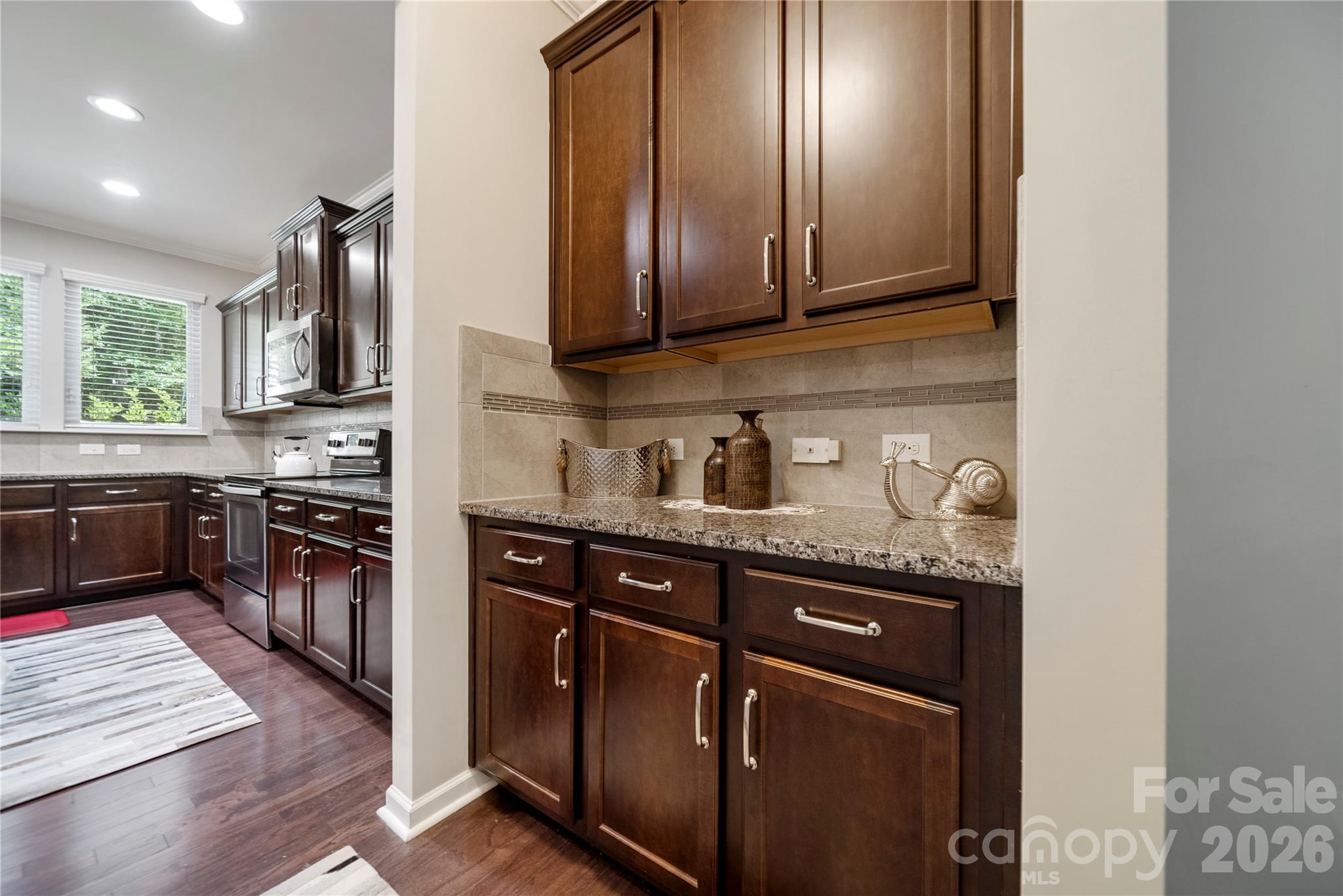 8122 Mossy Rock Road Waxhaw, NC 28173 - Photo 11 of 28 a kitchen with stainless steel appliances granite countertop wooden cabinets a stove top oven a sink and dishwasher