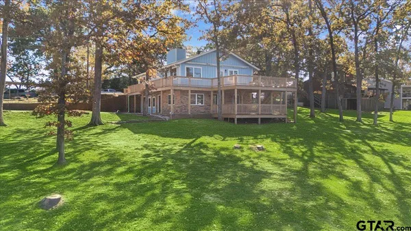 a view of a house next to a big yard and large trees
