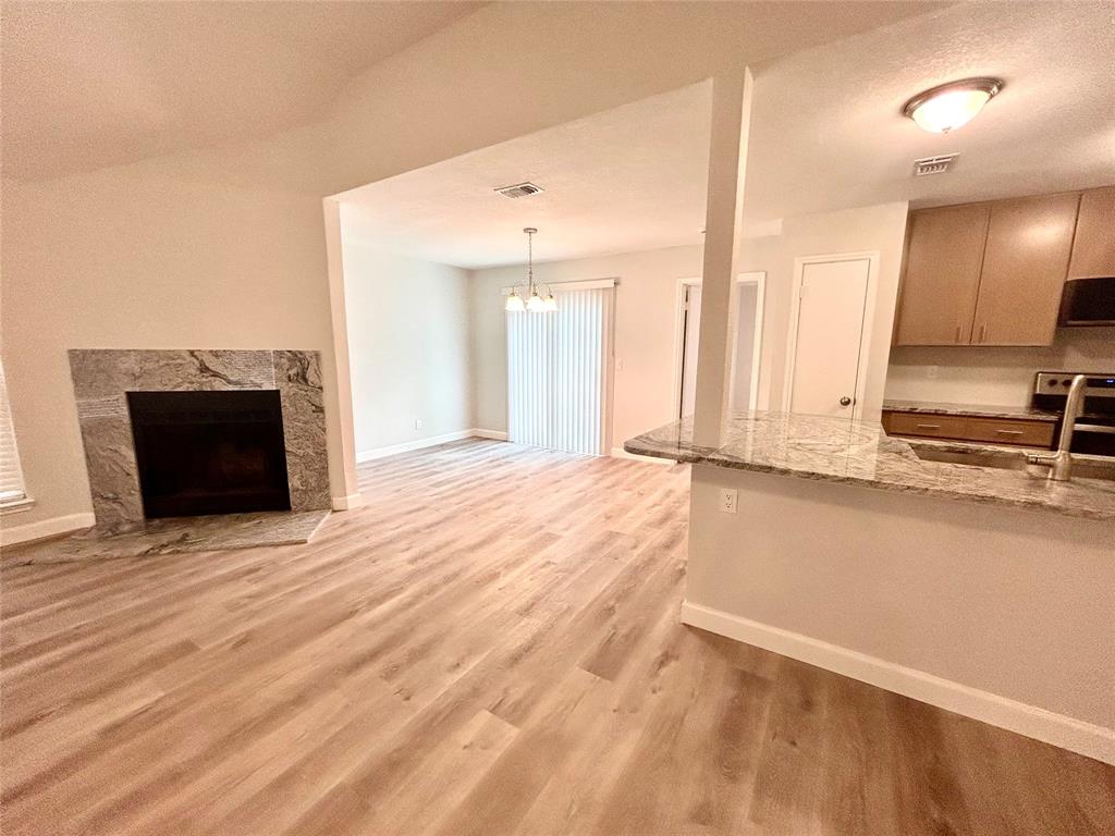 View of the living room, dining room and kitchen.  Beautiful granite fireplace.