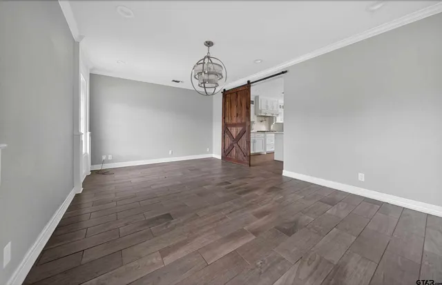 a view of a room with wooden floor chandelier and windows