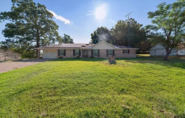 a view of a house with a yard and large trees