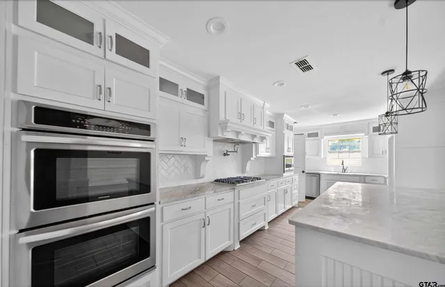 a kitchen with granite countertop white cabinets stainless steel appliances and a counter space
