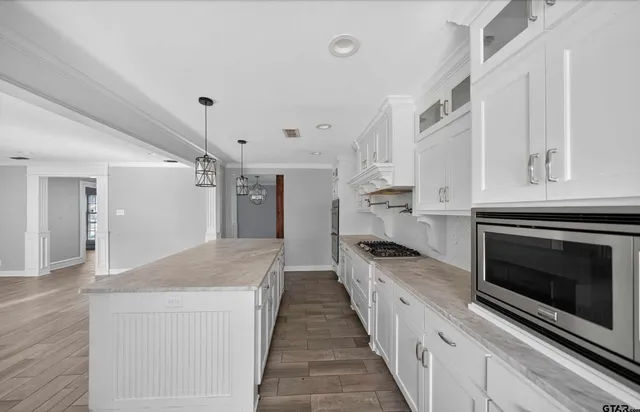 a large kitchen with granite countertop a stove top oven a sink dishwasher and a refrigerator with wooden floor