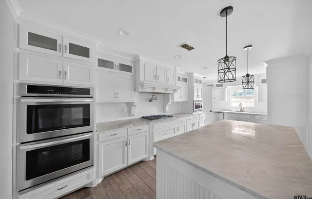 a kitchen with stainless steel appliances granite countertop a stove a sink and a microwave