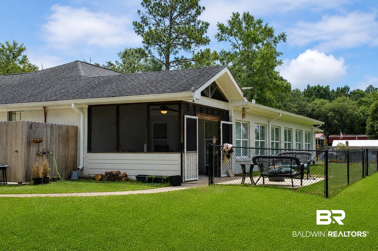 9825 Wolf Creek Ridge Elberta, AL 36530 - Photo 50 of 76 Expansive green lawn with a screened patio featuring a ceiling fan, a sunroom with multiple windows, a concrete patio, and a black chain link fence