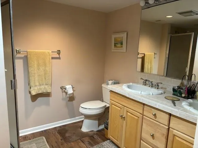 a bathroom with a granite countertop sink toilet and mirror