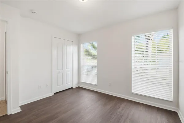 a view of an empty room with wooden floor and closet
