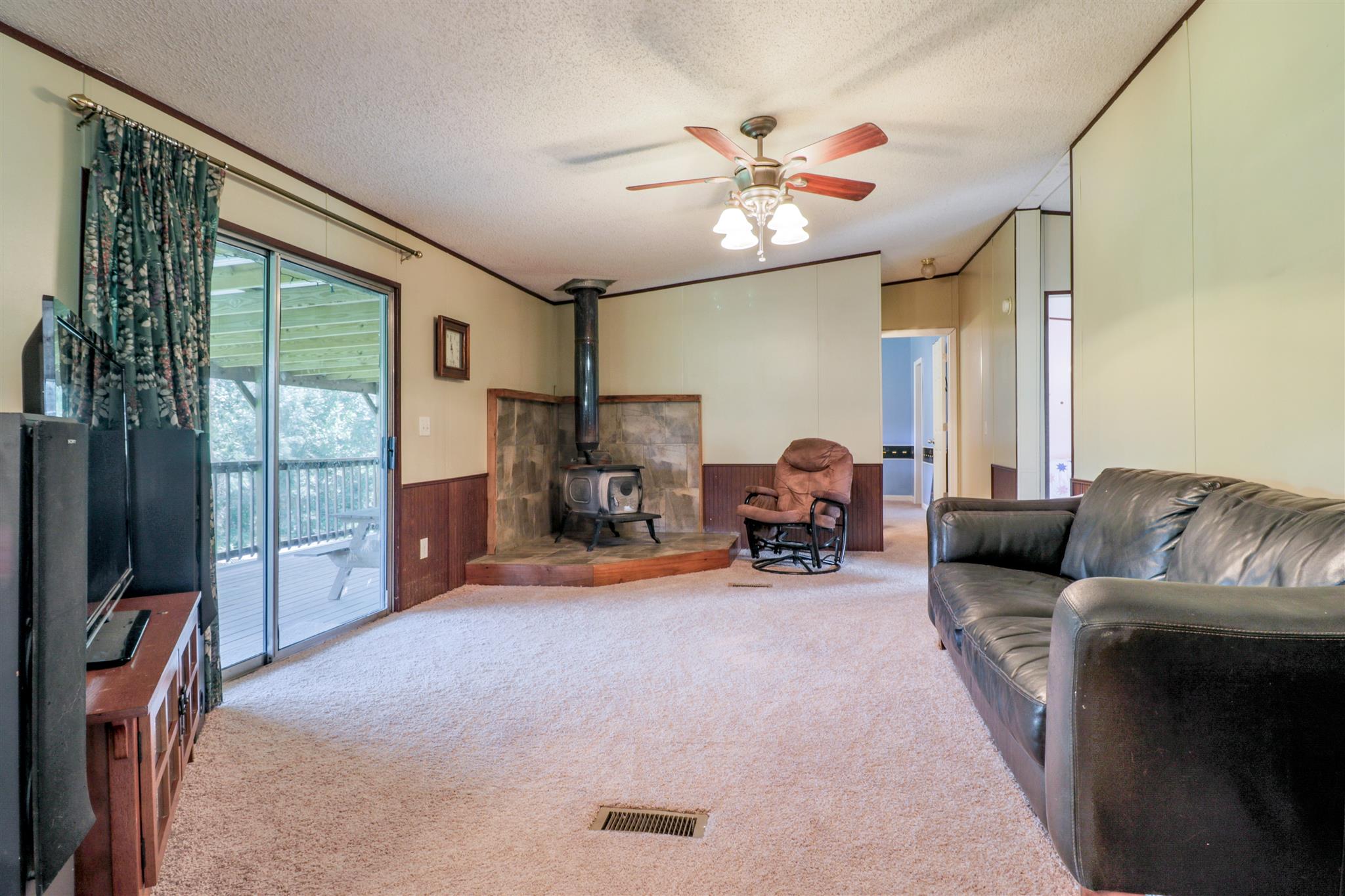 3268 Mobley Ridge Road Duck River, TN 38454 - Photo 13 of 19 Family room with wood burning stove and tinted sliding doors leading to huge covered back deck