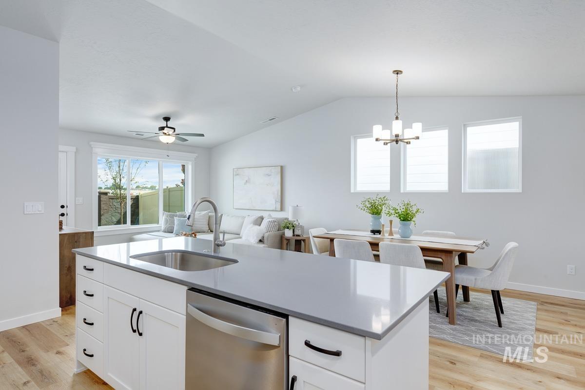 4309 South Zocalo Way Meridian, ID 83642 - Photo 7 of 26 Kitchen with white cabinets, stainless steel dishwasher, an island with sink, hanging light fixtures, and light wood-style flooring