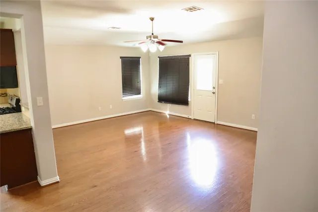 an empty room with wooden floor cabinet and windows