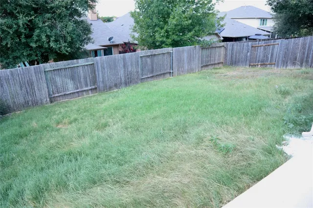 a view of a backyard with large trees and wooden fence