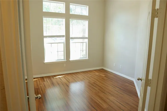 an empty room with wooden floor and windows