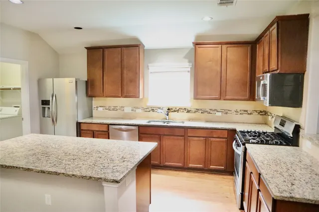 a kitchen with stainless steel appliances granite countertop a sink stove refrigerator and cabinets