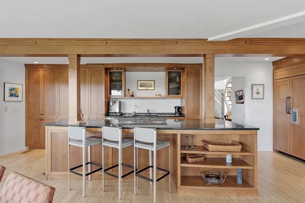a living room with stainless steel appliances kitchen island granite countertop furniture and a wooden floor