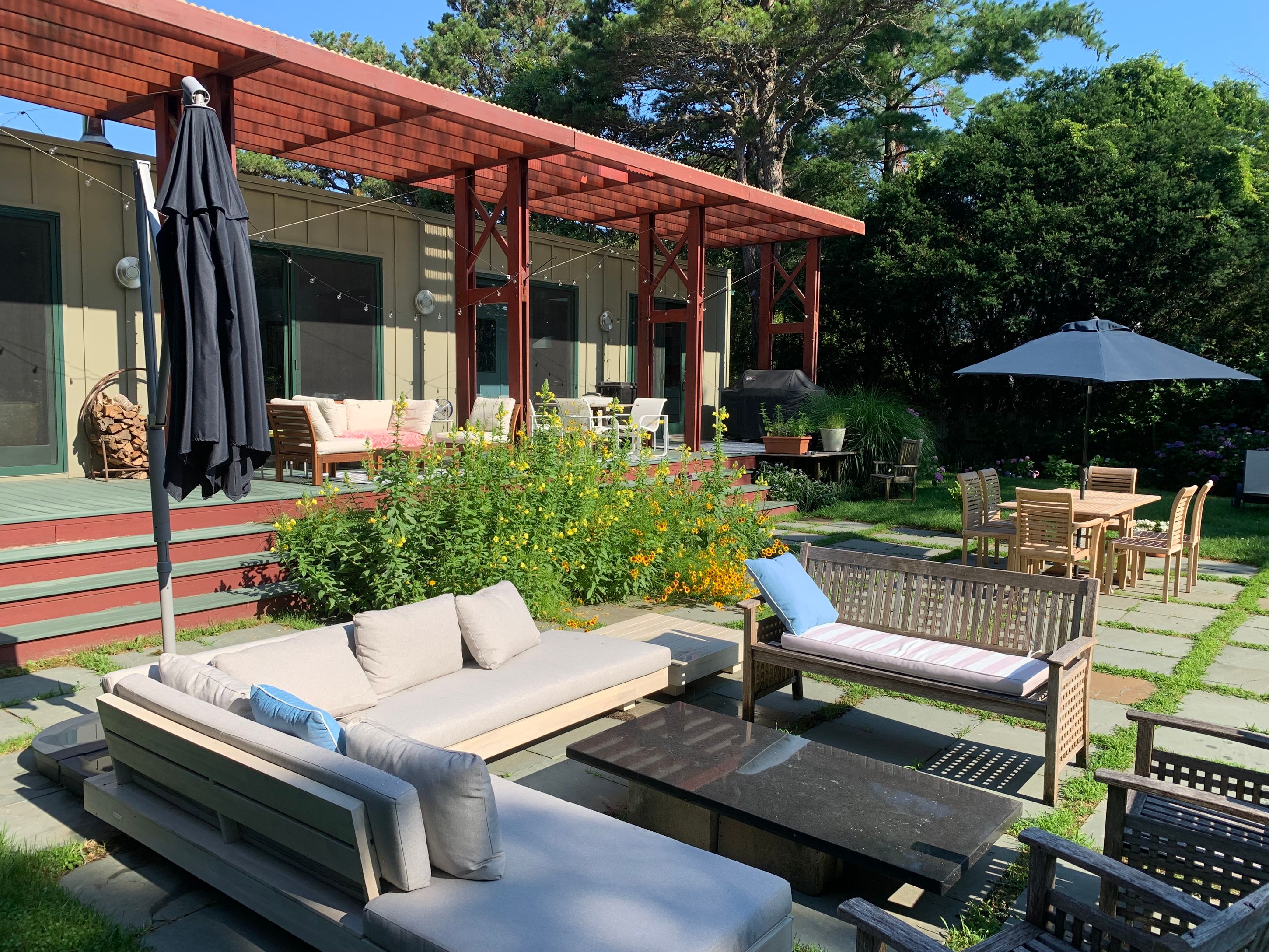 Undisclosed Address Sag Harbor, NY 11963 - Photo 14 of 18 a view of a patio with couches table and chairs under an umbrella with a fire pit
