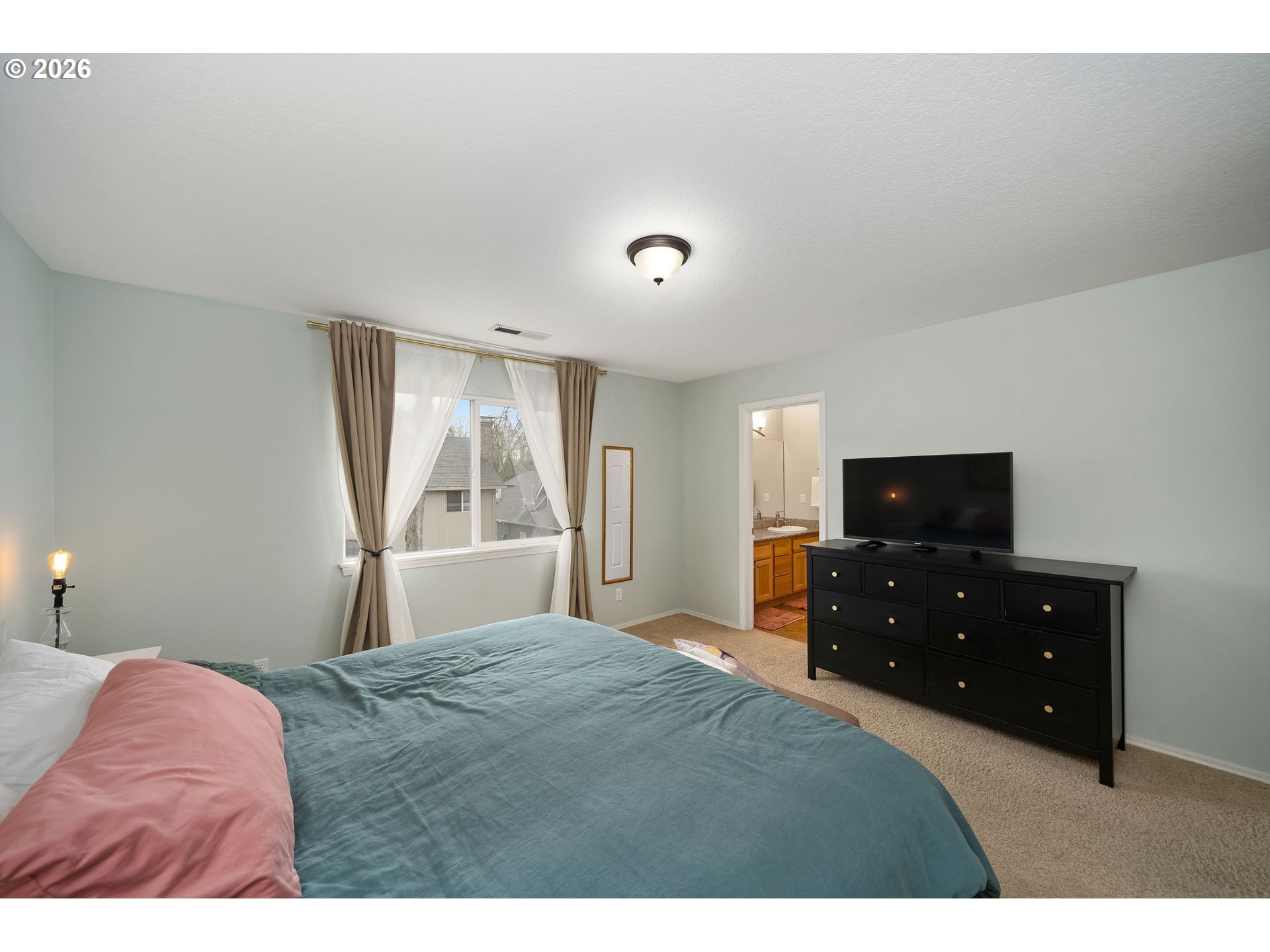 8330 Southwest Norfolk Lane Portland, OR 97224 - Photo 21 of 37 a bedroom with a bed and a flat tv screen on dresser