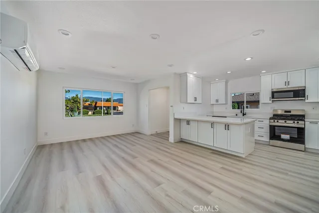 a large kitchen with stainless steel appliances granite countertop a stove a sink and white cabinets with wooden floor