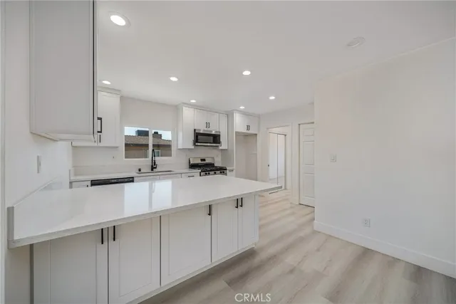 a kitchen with stainless steel appliances a sink a stove a refrigerator and cabinets