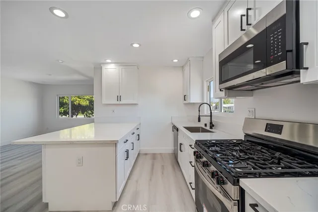 a kitchen with stainless steel appliances granite countertop a stove a sink and a microwave
